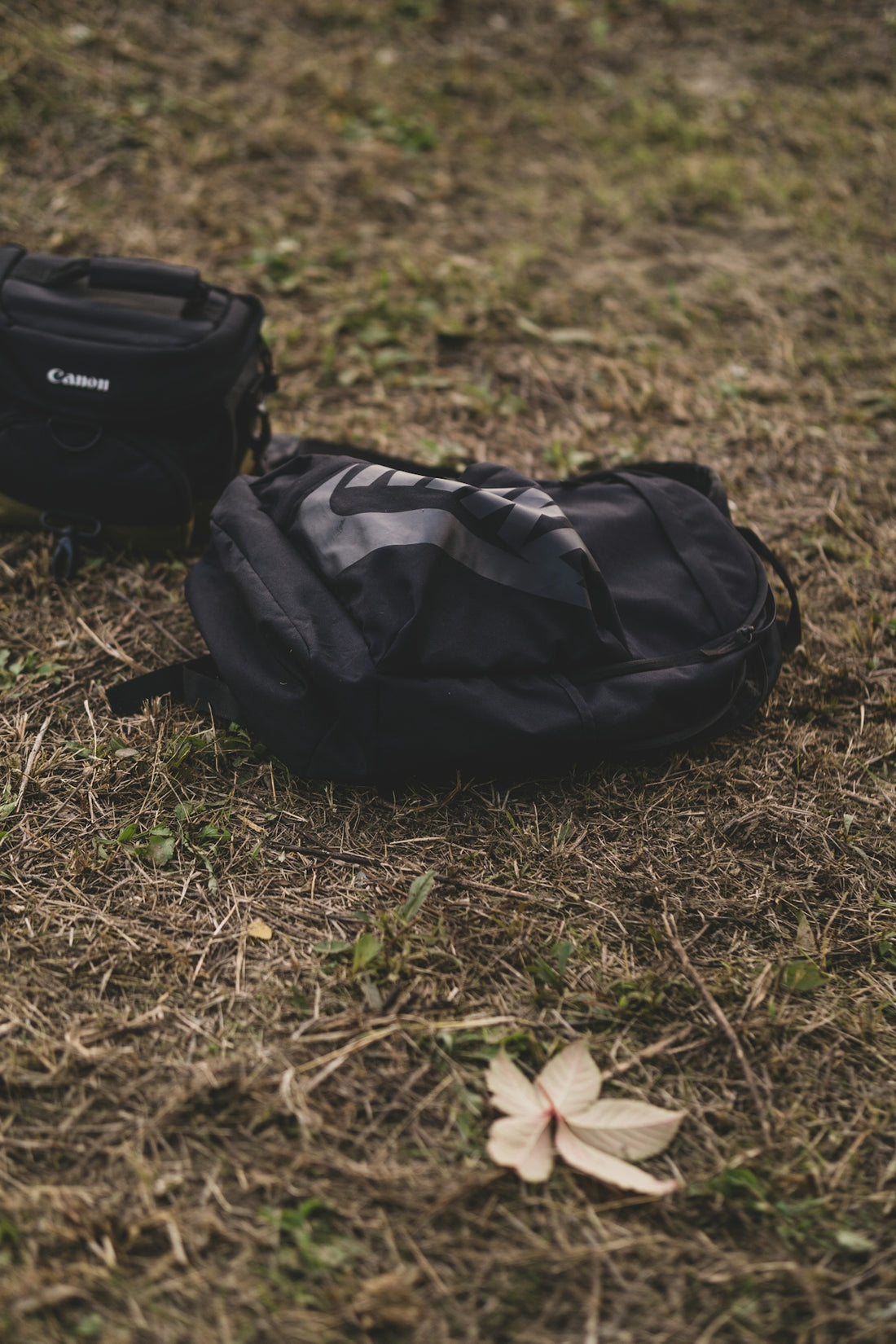 a black backpack sitting on top of a grass covered field