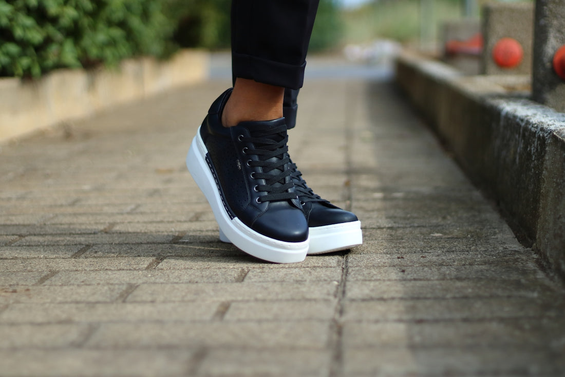 a person standing on a brick walkway wearing black and white sneakers