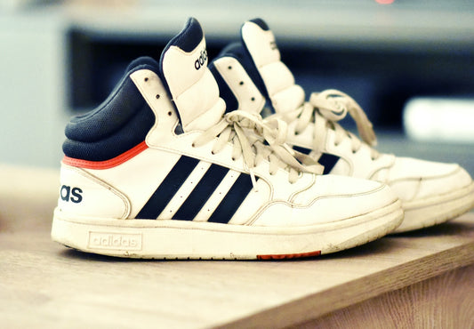 a pair of white and blue sneakers sitting on top of a wooden table