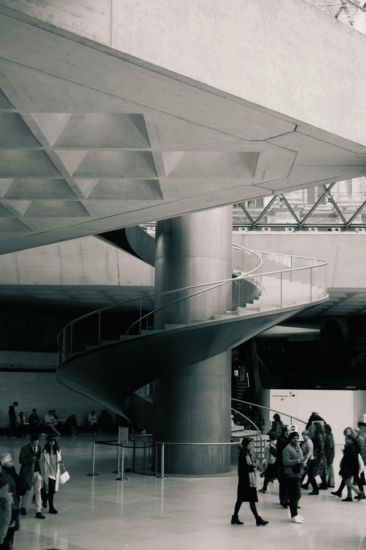 Interno moderno con scalinata a spirale e persone che passeggiano in un ambiente architettonico elegante.