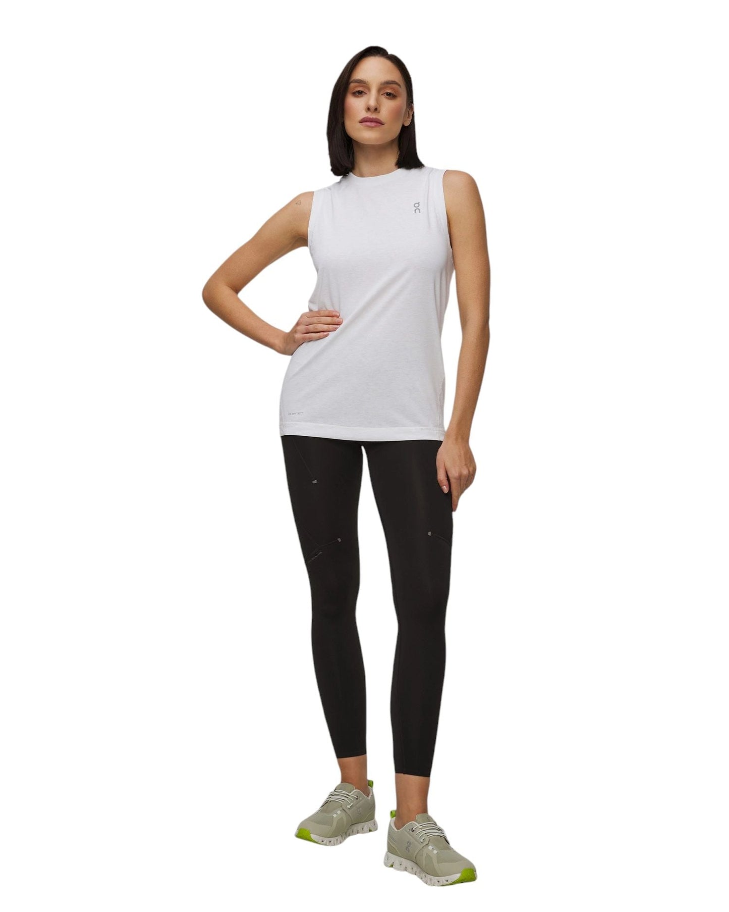 Modella in top bianco e leggings neri che indossa scarpe sportive colorate. Outfit sportivo elegante.