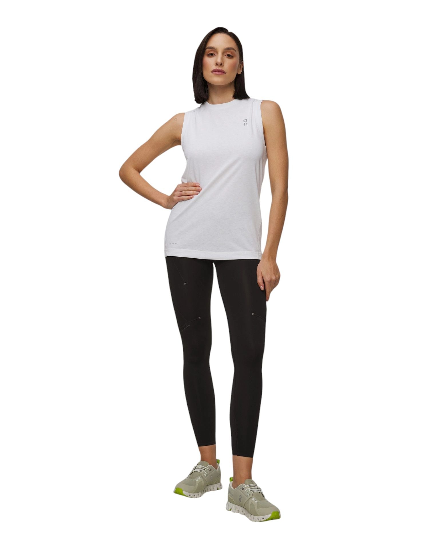 Modella in top bianco e leggings neri che indossa scarpe sportive colorate. Outfit sportivo elegante.
